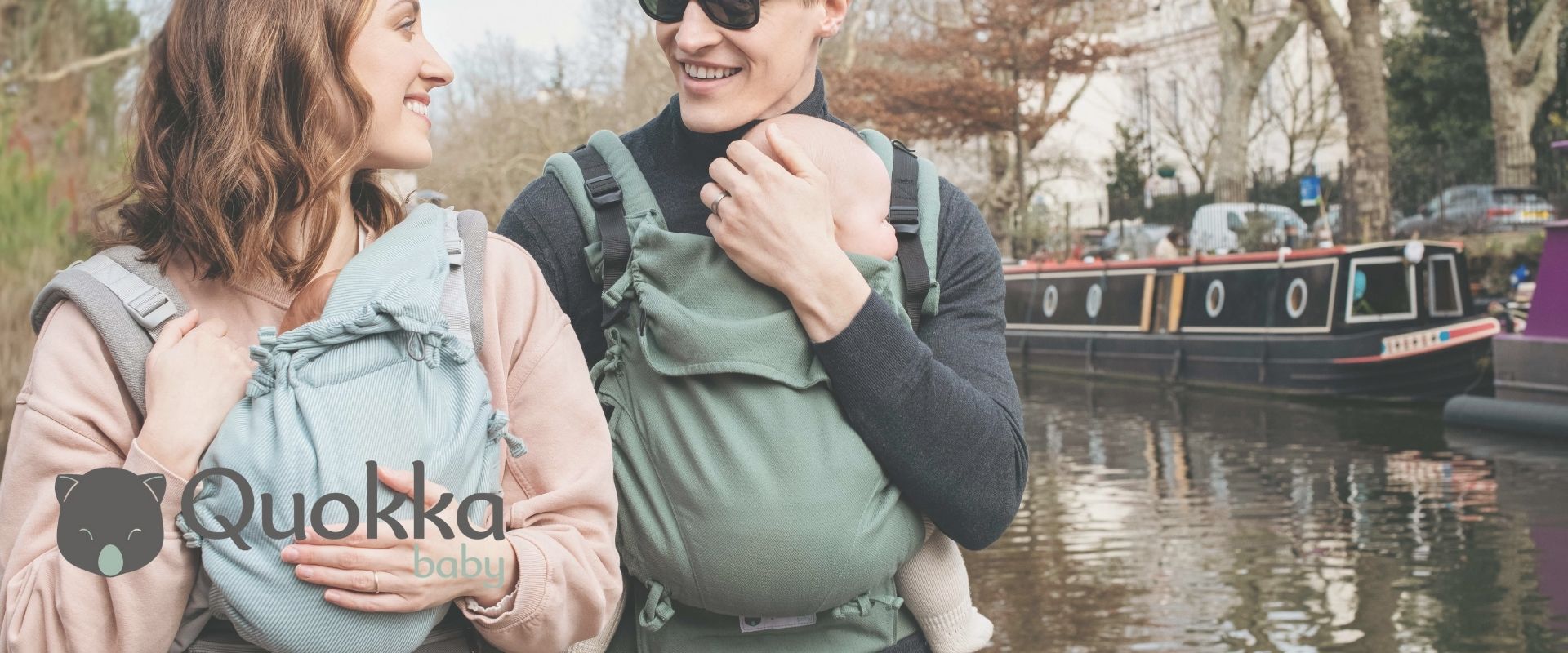 mochila portabeb&eacute;s e Carrier en accion con dos padres porteando a bebes de diferentes edades 